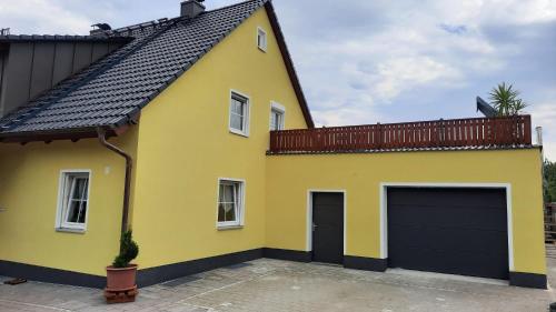 a yellow house with a black garage at Ferienwohnung Erika in Waischenfeld