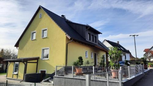 ein gelbes Haus mit schwarzem Dach in der Unterkunft Ferienwohnung Erika in Waischenfeld