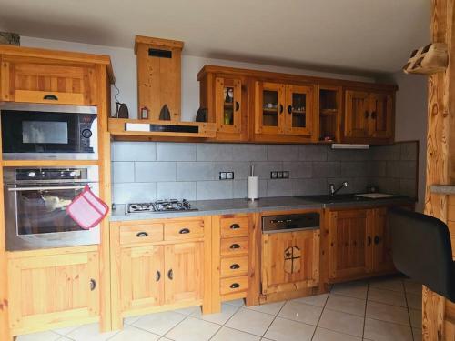 a kitchen with wooden cabinets and a stove top oven at Le Banc Des Seilles in Bonvillard
