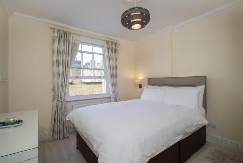 een slaapkamer met een groot bed en een raam bij Marylebone Village Apartments in Londen
