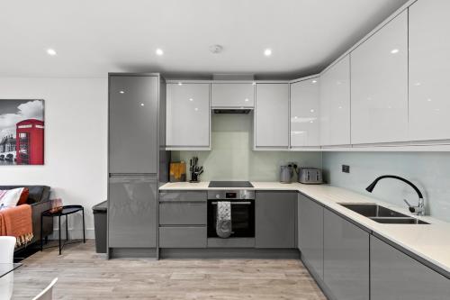 a kitchen with white cabinets and a living room at Star London Vivian Avenue 2-Bed Retreat with Garden in The Hyde