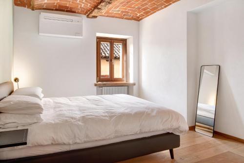 a white bedroom with a bed and a mirror at Vicolo 10 in Asti