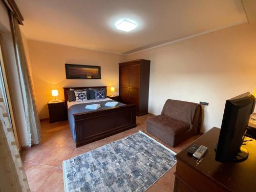 a bedroom with a bed and a chair and a television at Villa Beatrix Budva in Budva