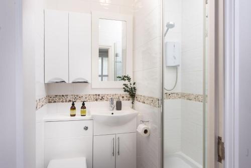 een witte badkamer met een wastafel en een douche bij The Manor in Uny Lelant