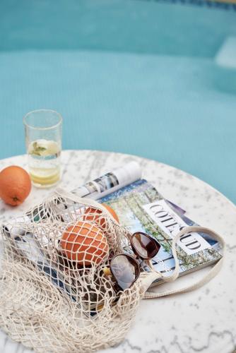 a table with a newspaper and a basket with sunglasses and a magazine at Hotel Ippoliti in Nafplio