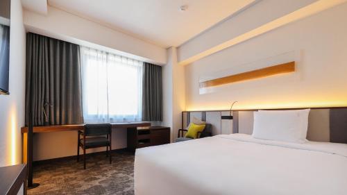 a hotel room with a bed and a desk at ANA Holiday Inn Sendai by IHG in Sendai