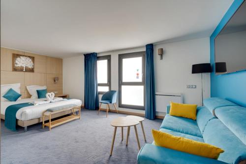 Habitación de hotel con sofá azul y cama en Hotel du Golf Coignieres, en Coignières