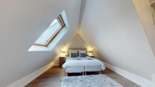 Schlafzimmer im Dachgeschoss mit einem Bett und einem Fenster in der Unterkunft LE NID DE L'ILL, Magnifique Duplex Cosy Petite France in Straßburg