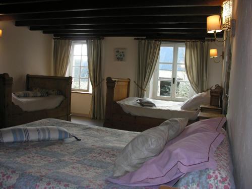 a bedroom with two beds and two sinks and windows at Ferme de Savigny in La Cambe