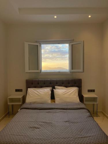 a bedroom with a large bed with a window at Skala Sunset Hotel and spa in Ios Chora