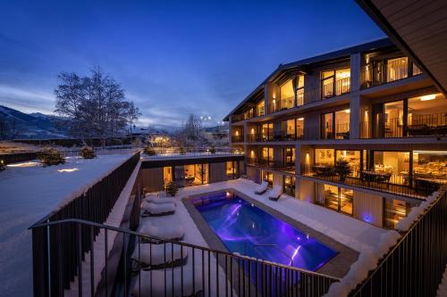 a building with a swimming pool in the snow at Emma Deluxe Aparthotel ganzjährig beheizter Außenpool in Piesendorf