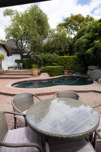a patio with a table and chairs and a swimming pool at Cape Village Lodge in Durbanville