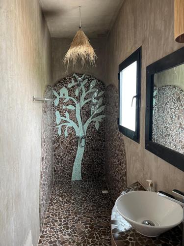 un baño con un mural de árbol en la pared y un lavabo en Bine Bassile, en Guéréo