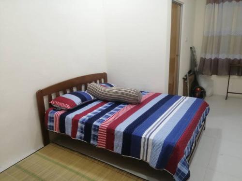 un letto con una coperta a righe e due cuscini sopra di Homestay Insan a Melur