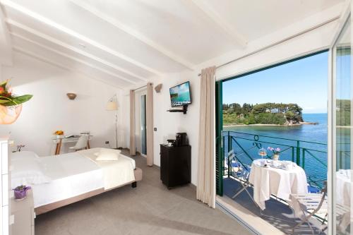 una camera con letto e un balcone con vista di Hotel Villa Domizia a Porto Santo Stefano