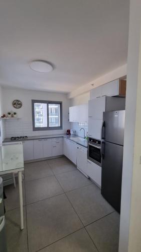 Apartment Sandarella في بات يام: مطبخ بخزائن بيضاء وثلاجة سوداء