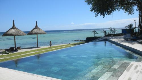 a swimming pool with the ocean in the background at Sunset Coast Apartment in Rivière Noire