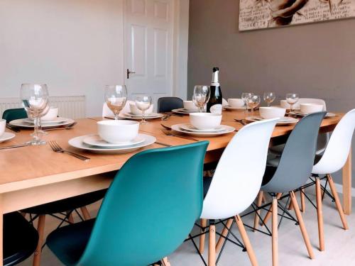 a wooden table with chairs and a bottle of wine at Spacious 5-Bedroom Home with Garden & Parking Near Station in Coventry