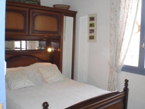 1 dormitorio con 1 cama con cabecero de madera y ventana en Le bastidon du grand chene, en Pontevès