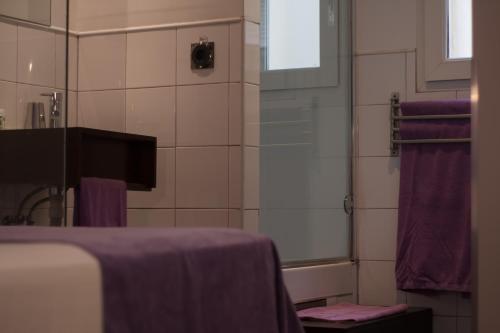 a bathroom with a sink and a shower with purple towels at Hostal Santa Ana Colors in Madrid