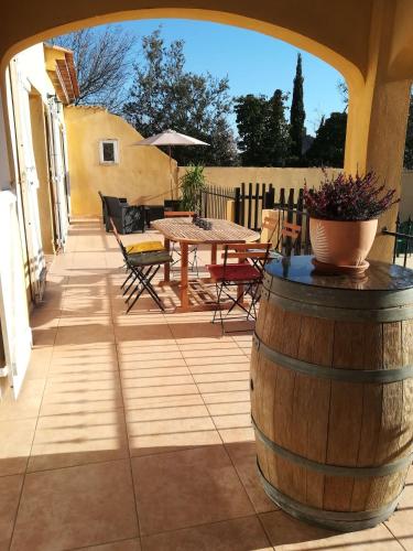 a patio with a table and chairs and a barrel at Chez TATA in Régusse