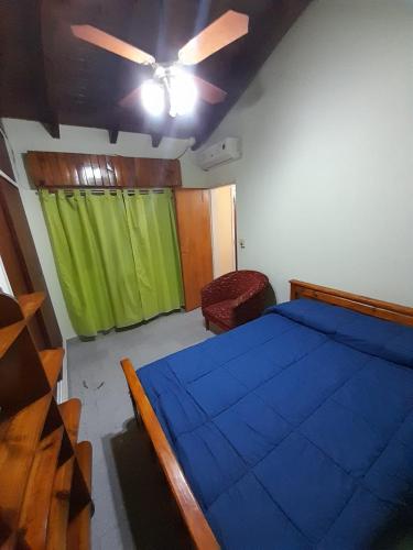 1 dormitorio con cama azul y cortina verde en MB Alojamiento Alta Barda en Neuquén