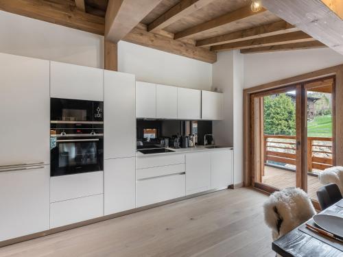 une cuisine avec des placards blancs et une grande fenêtre dans l'établissement Appartement élégant près des pistes avec sauna, hammam, salle de sport et parking couvert - FR-1-569-47, à Megève