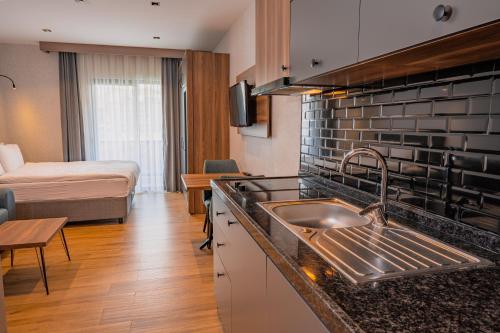 a kitchen with a sink and a room with a bed at Görükle Alpaş Yaşam Hotel in Bursa