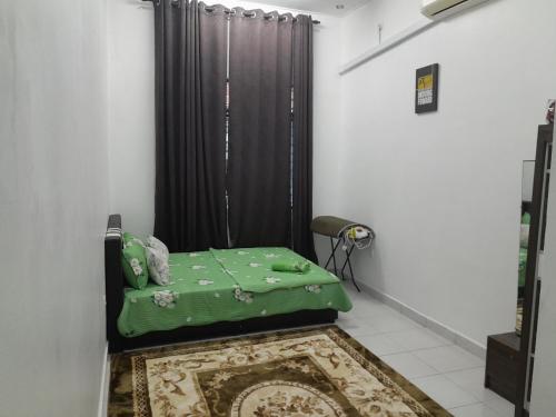 Zimmer mit einem grünen Bett und einem schwarzen Vorhang in der Unterkunft Homestay Muslim D Permata Izhansif in Bandar Penawar