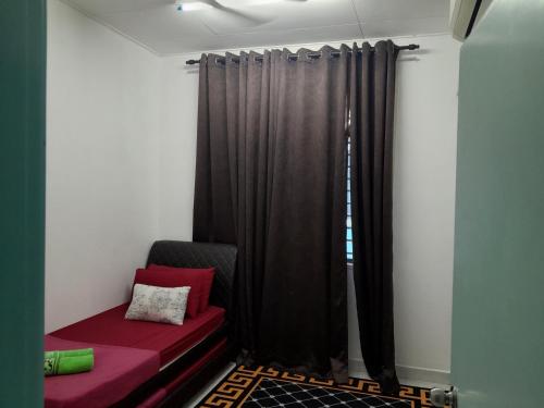 ein Zimmer mit einem roten Sofa und einem Fenster in der Unterkunft Homestay Muslim D Permata Izhansif in Bandar Penawar