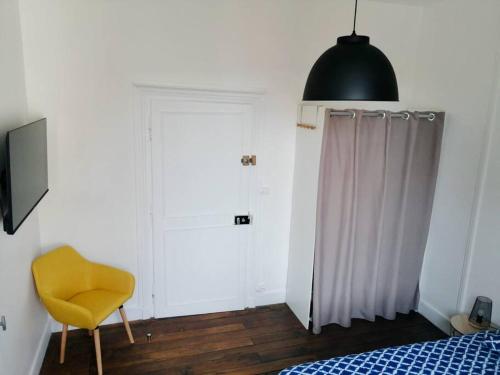 - une chambre avec un lit et une chaise jaune dans l'établissement Uluru by iZiLi Centre Ville Poitiers, à Poitiers