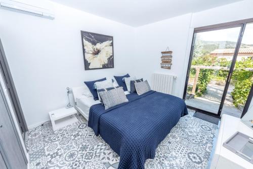 une chambre avec un lit bleu et une grande fenêtre dans l'établissement Villa Le Bastidou, au Plan-de-la-Tour