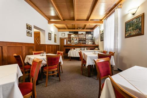 une salle à manger avec des tables et des chaises blanches dans l'établissement Vila Vyšehrad, à Luhačovice