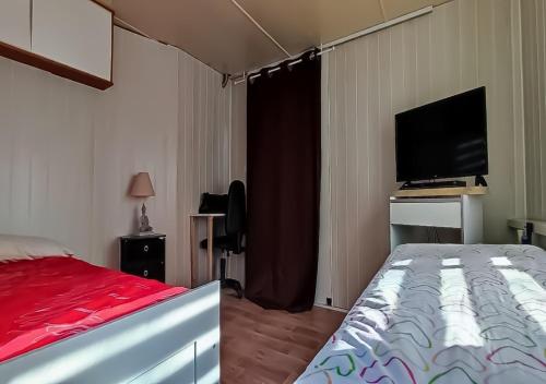 une chambre avec un lit et une télévision à écran plat dans l'établissement superbe mobil home, climatisé, ss vis a vis, au calme, dans super domaine, à Fréjus