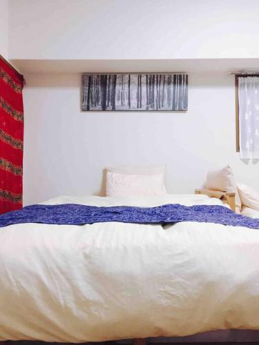 a bedroom with a white bed with a blue blanket at First Hiroshima in Hiroshima