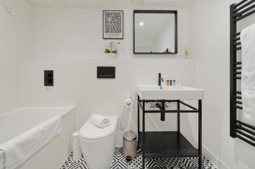 ein weißes Bad mit einem Waschbecken und einem WC in der Unterkunft Luxury one bedroom Greenwich studio apartment near Canary Wharf by UnderTheDoormat in London