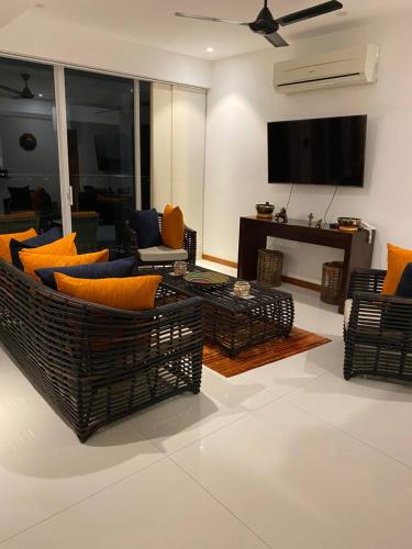 a living room with couches and a flat screen tv at Luxury Penthouse, Nilaveli in Trincomalee