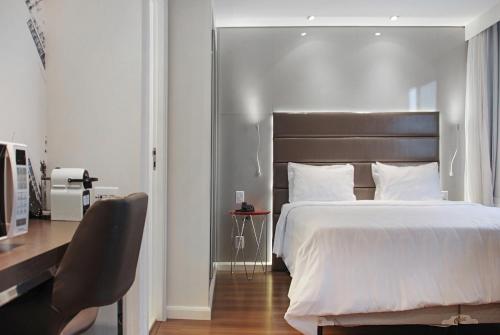 a bedroom with a large white bed and a desk at Exuberante hotel na Vila Olimpia in Sao Paulo