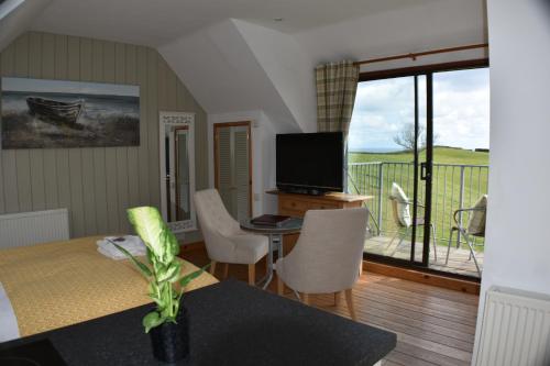 a living room with a table and a television and a balcony at Frogwell in Strete