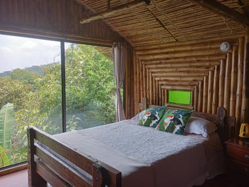 a bedroom with a bed with a large window at Finca Colibrí Zafiro, Altos del Rosario in Cali