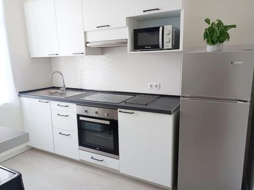 een witte keuken met een koelkast en een magnetron bij Herba de namorar- Céntrico apartamento en Cedeira in Cedeira