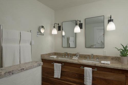 a bathroom with two sinks and two mirrors at The Lodge at Moosehead Lake in Greenville