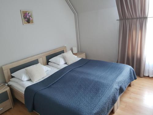a bedroom with a blue bed with white pillows at Hotel Melturi in Melturi