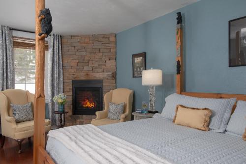 a bedroom with a bed and two chairs and a fireplace at The Lodge at Moosehead Lake in Greenville