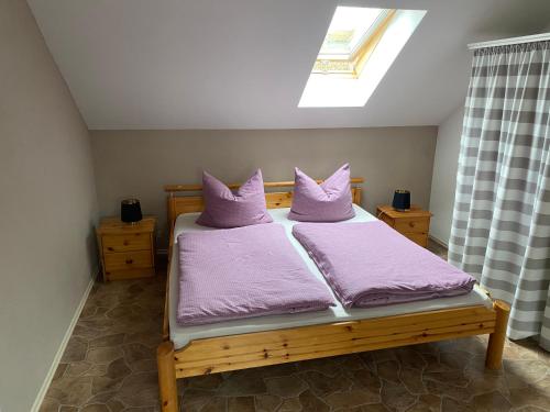 um quarto com uma cama com almofadas roxas e uma janela em Ferienwohnung Franz Jäger Berlin em Gützkow