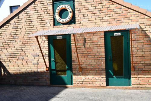 a brick building with green doors and a clock on it at Balders Bude 2 in Mönkebude