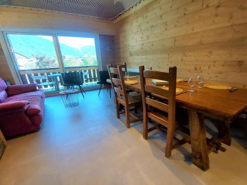 une salle à manger avec une table et des chaises en bois dans l'établissement Appartement rénové avec mezzanine et balcon au cœur de Samoëns, idéal pour famille nombreuse - FR-1-624-69, à Samoëns