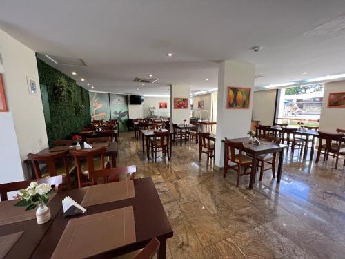 a restaurant with wooden tables and chairs in a room at Hotel Ema Palace in São José dos Campos