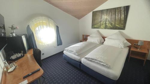 Schlafzimmer mit einem Bett, einem TV und einem Fenster in der Unterkunft KRYSTALL Hotel in Filderstadt