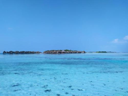 a view of the ocean with houses in the background at Courtyard Guesthouse in Huraa
